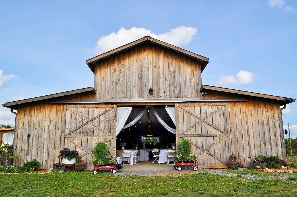 Double barn doors on either end of Kris Cobb's Barn at Drewia Hill in Sale Creek roll open to allow picturesque views of sunsets and the rolling hills of the 800-tree peach orchard.