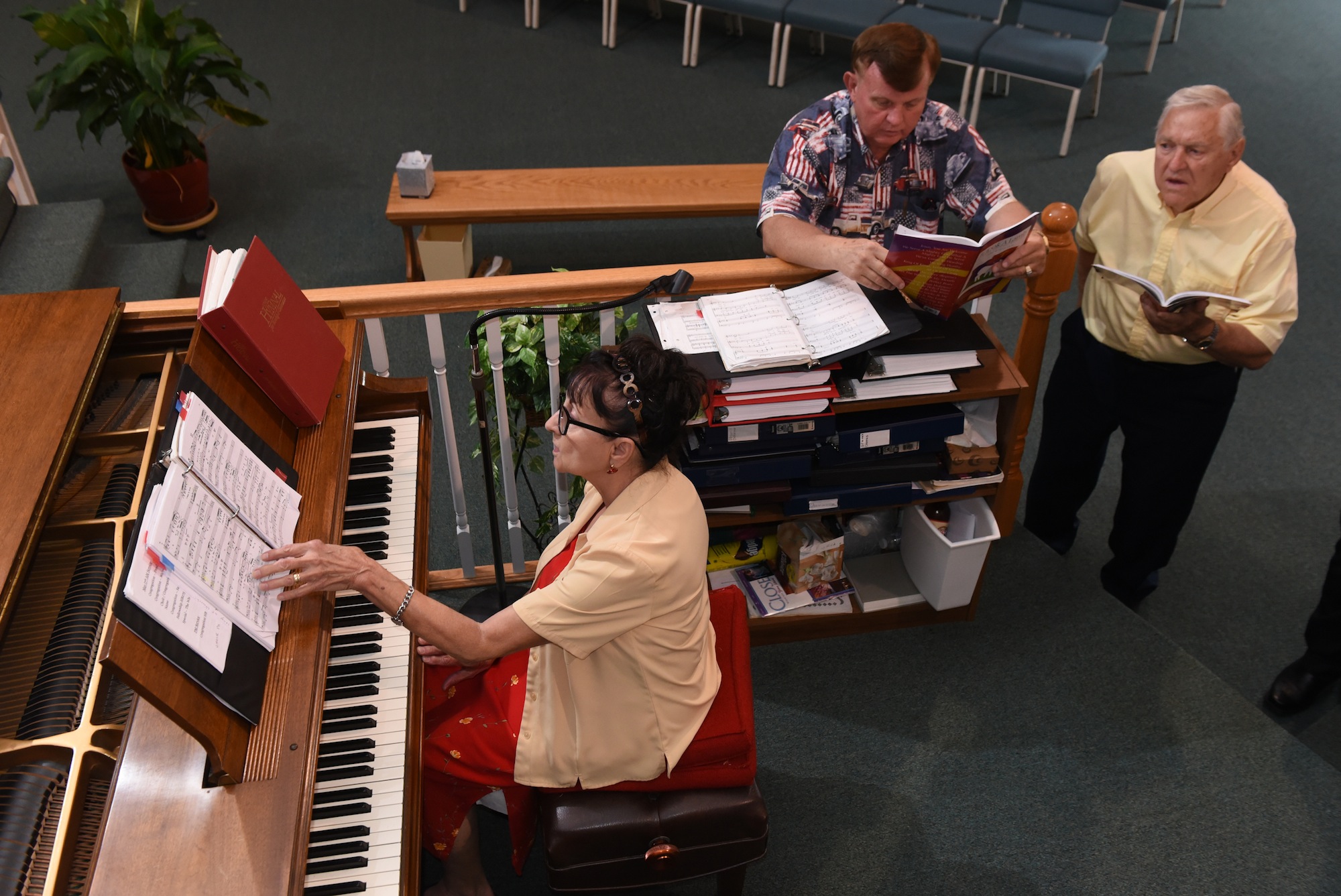 June Edmondson helps choir members Dennis Bowman, center, and Charlie Ramsey work on their vocal parts during choir practice.
