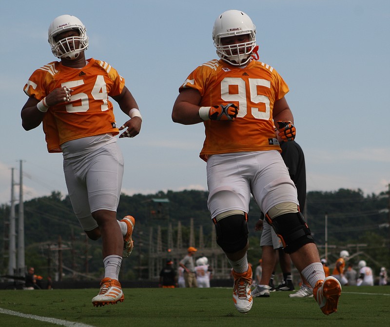 University of Tennessee defensive linemen Jordan Williams (54) and Danny O'Brien (95) jog back toward their lines during practice at Haslam Field on Friday.