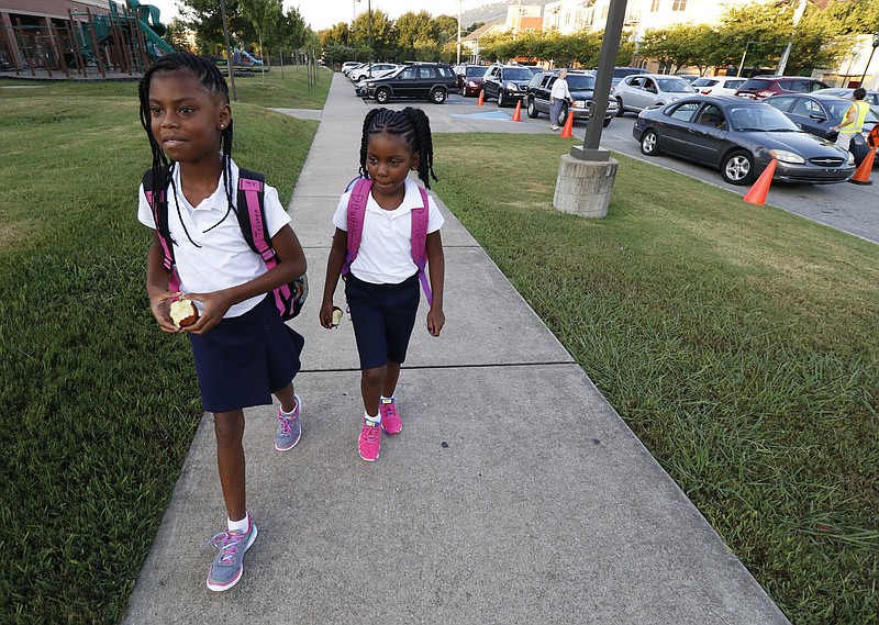 Fourth grade student Tristyn Vaughn walks her sister Kassidy Douglas to the first grade hall during the first day of school on Thursday, August 13, 2015 at Battle Academy. 
