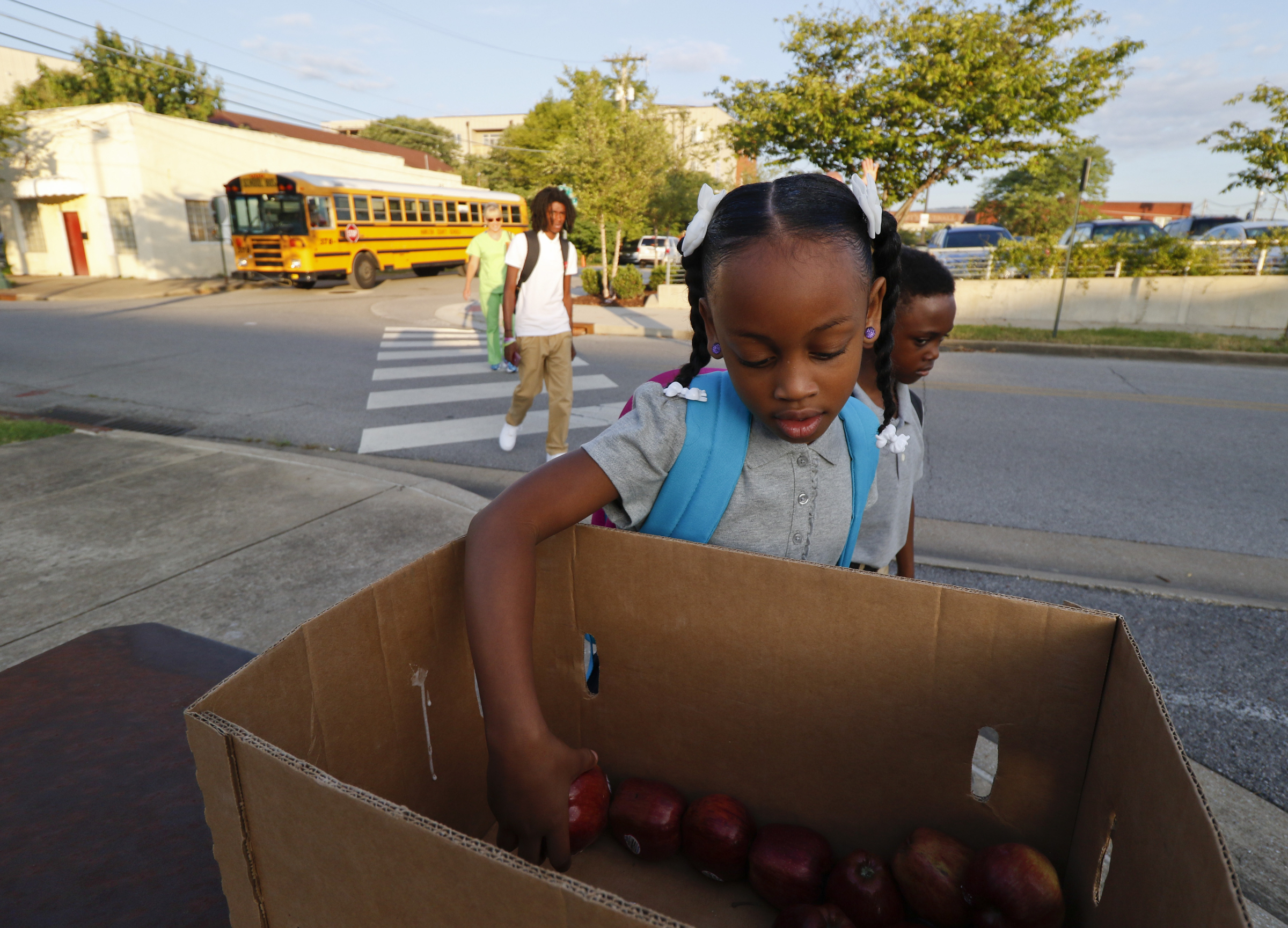 First grader Sky McKinney grabs an apple while walking onto campus during the first day of school on Thursday, August 13, 2015 at Battle Academy.