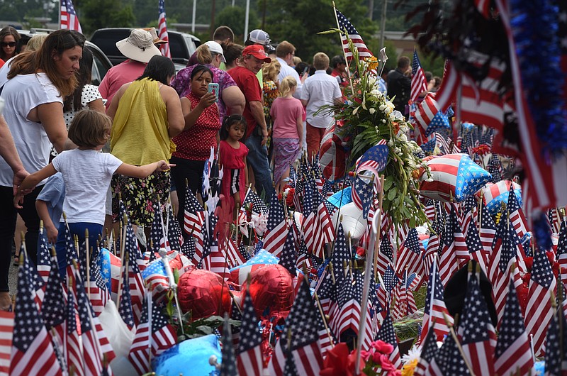 People gather at a memorial in front of the Armed Forces Career Center on Lee Highway on Sunday, July 19, 2015, in Chattanooga, Tenn., in the aftermath of a Thursday terrorist attack that killed four Marines and one member of the U.S. Navy.