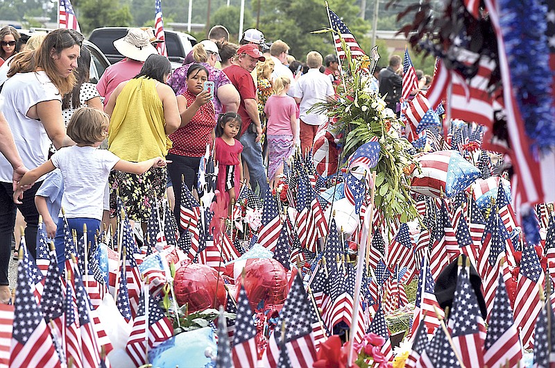 People gather at a memorial in front of the Armed Forces Career Center on Lee Highway on Sunday, July 19, 2015, in Chattanooga, Tenn., in the aftermath of a terrorist attack that killed four Marines and one member of the U.S. Navy.