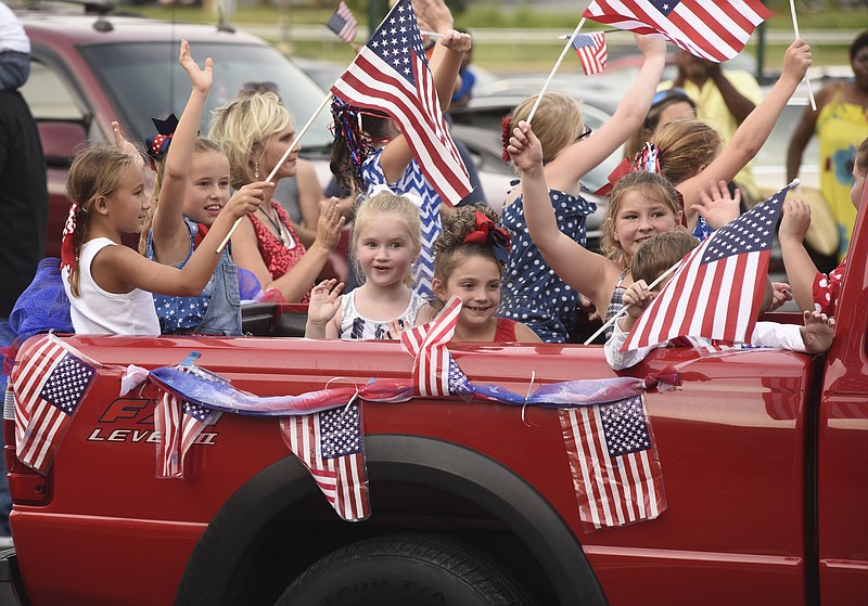 A pickup truck load of students from the Ginger Brown Academy of Performing Arts wave American flags during a "Chattanooga Strong" parade at Hamilton Place Mall on Sunday, Aug. 16, 2015, in Chattanooga.