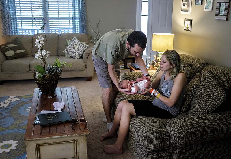 Laura Marsh hands her husband Danny their newborn son, Elias, in the living room after the couple brought him home from Erlanger Hospital on Tuesday, Aug. 11, 2015, to their home in East Ridge, Tenn. Elias, who will be called "Eli," is the Marsh's first child.