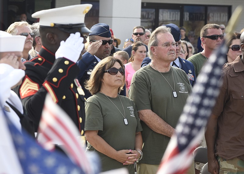 Betty and Jerry Sullivan, parents of slain U. S. Marine Sullivan watch while an American flag is raised during an opening ceremony Sunday, Aug. 16, 2015, in Chattanooga, Tenn., at a memorial to the five servicemen who were killed on July 16. U. S. Marine Sgt. Demonte Cheeley, who was wounded in the attack, salutes at left. 