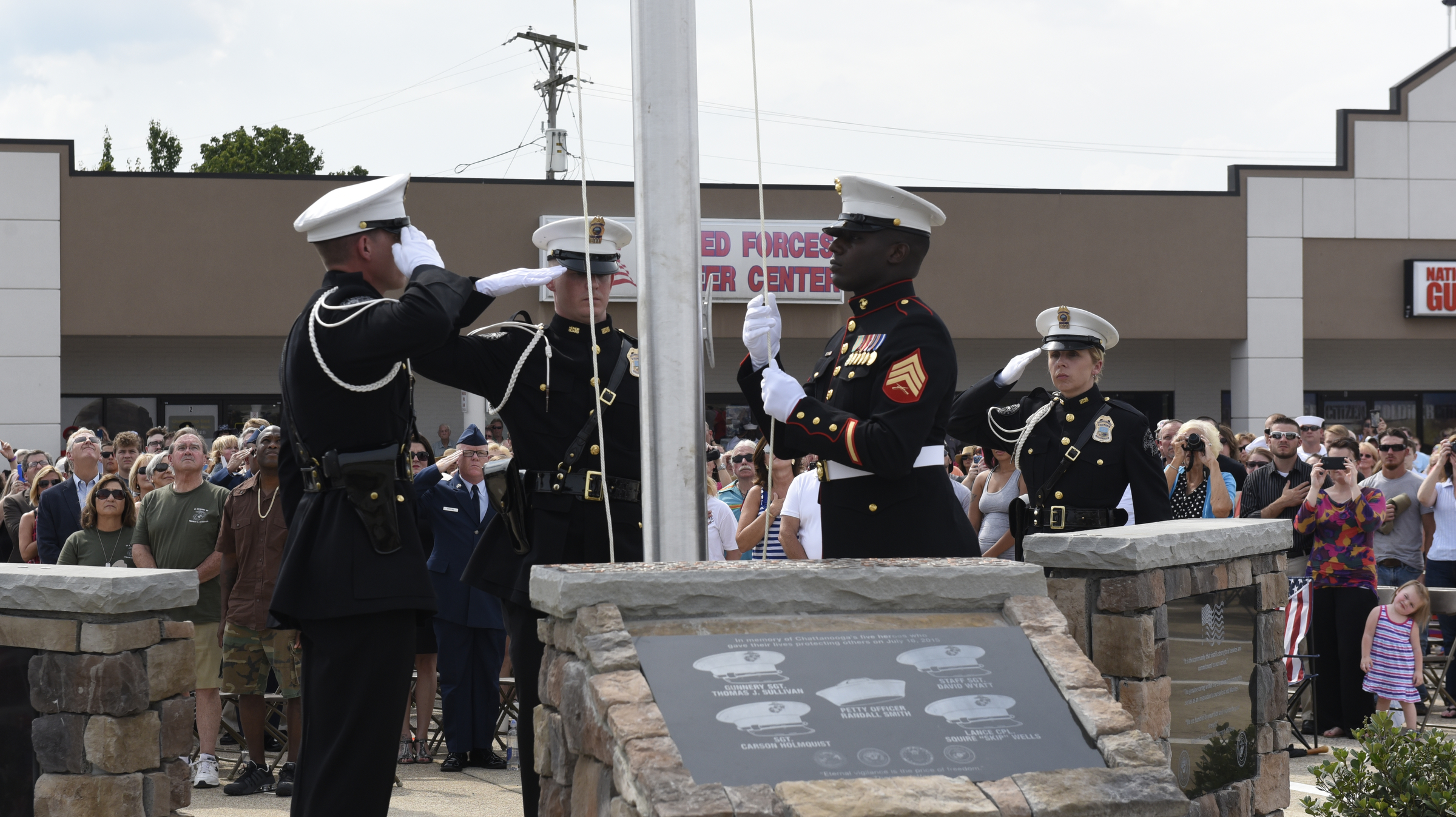 U. S. Marine Sgt. Demonte Cheeley raises an American flag during an opening ceremony Sunday, Aug. 16, 2015, in Chattanooga, Tenn., at a memorial to the five servicemen who were killed on July 16. Sgt. Cheeley, who was wounded in the attack, is assisted by members of the Chattanooga Police Department Honor Guard, from left, Christopher Grafe, Lance Lockhart and Jamie Barrow. The memorial is located at 6219 Lee Highway near the Armed Forces Career Center where the July attack began.