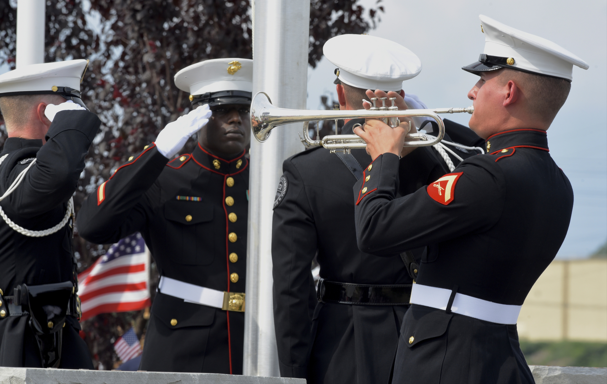 U. S. Marine Sgt. Demonte Cheeley, center, salutes while Marine Lance Cpl. James Draffen plays "Taps" after the raising of an American flag during an opening ceremony Sunday, Aug. 16, 2015, in Chattanooga, Tenn., at a memorial to the five servicemen who were killed on July 16. Sgt. Cheeley, who was wounded in the attack, was assisted in the flag-raising by members of the Chattanooga Police Department Honor Guard. The memorial is located at 6219 Lee Highway near the Armed Forces Career Center where the July attack began.