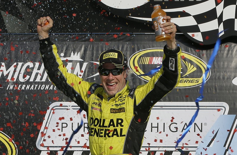 Matt Kenseth raises his arms in victory lane after winning the NASCAR Sprint Cup series auto race at Michigan International Speedway, Sunday, Aug. 16, 2015, in Brooklyn, Mich.