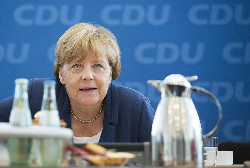 
              German Chancellor Angela Merkel puts down her handbag under her table at the beginning of a board meeting of her Christian Democratic Union party, CDU, at the party's headquarters in Berlin, Germany, Monday, Aug. 17, 2015. (AP Photo/Gero Breloer)
            