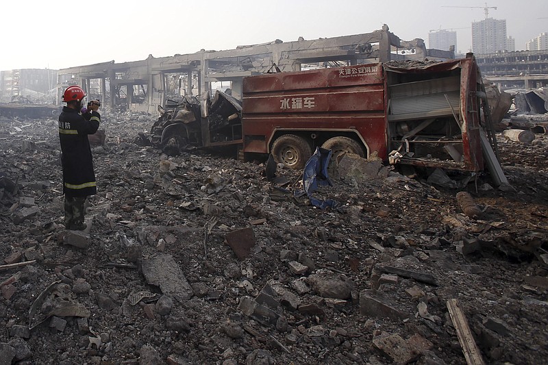 
              In this photo taken Saturday Aug. 15, 2015, a firefighter inspects a destroyed fire truck at the site of an explosion in northeastern China's Tianjin municipality. The rapid chain of explosions that destroyed a warehouse district in the Chinese port of Tianjin could become one of the world’s deadliest disasters for fire crews. Now questions are being raised about whether the crews were properly trained and equipped to deal with the emergency at a warehouse that stored a volatile mix of chemicals, including compounds that become combustible on contact with water. (Chinatopix Via AP) CHINA OUT
            