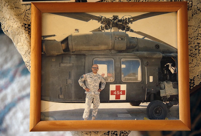 
              This March 17, 2015 photo shows a photgraph of now-retired U.S. Army Sgt. 1st Class Marshall Powell standing with a U.S. Army MEDEVAC helicopter in Iraq during his last tour to the country, at Powell's brother's house in Crescent, Okla. Powell, who served as a military nurse in Iraq and Afghanistan, was deeply haunted by his experiences, and nearly lost his own internal war with depression before finding meaningful help. (AP Photo/Brennan Linsley)
            