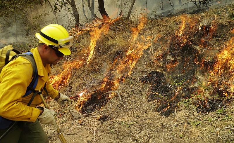 
              Washington National Guard Sgt. Danny Redington uses a flare to light controlled back burns as he fights the First Creek Fire, Tuesday, Aug. 18, 2015, near Chelan, Wash. The troops in Washington state were part of a massive response to blazes burning throughout the West. (AP Photo/Ted S. Warren)
            