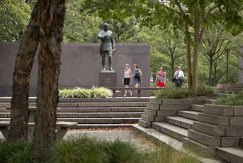 
              People walk past a statue of Gen. John J. Pershing, who had served as general of the Armies in World War I, in Pershing Park, at 14th Street and Pennsylvania Avenue NW, in Washington, Wednesday, Aug. 19, 2015. A jury has selected five design concepts for a new national World War I Memorial to be built in the memorial park in Washington, with ideas ranging from neoclassical architecture to a portrait wall of the "American family." Congress has dedicated the existing park along Pennsylvania Avenue near the White House to become a national memorial honoring the veterans of the first world war and the 116,516 American lives lost. A design competition drew 350 entries, and a jury narrowed those to five finalists announced Wednesday. (AP Photo/Carolyn Kaster)
            
