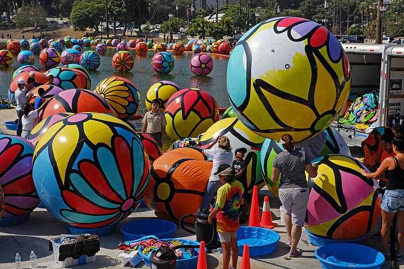 
              Volunteers inflate spheres to be lowered into Los Angeles’ MacArthur Park Lake as part of a public art installation by Portraits of Hope on Saturday, Aug. 22, 2015. The installation will feature about 3,000 inflatable, hand-painted spheres. The vinyl, beach-ball-like orbs were painted by hand earlier this summer by about 10,000 volunteers, including hospital patients, students from nearby schools and youths who took part in the Special Olympics. (AP Photo/Richard Vogel)
            