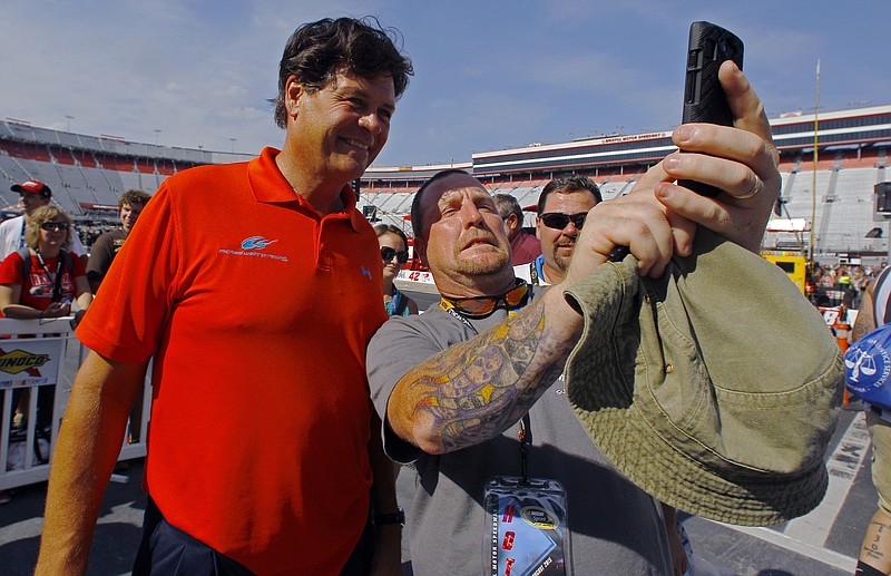 
              Former owner/driver Michael Waltrip, left, has a photo taken with fan David Secore Jr., from Union, Conn., before a NASCAR Sprint Cup Series auto race, Saturday, Aug. 22, 2015, in Bristol, Tenn. (AP Photo/Wade Payne)
            
