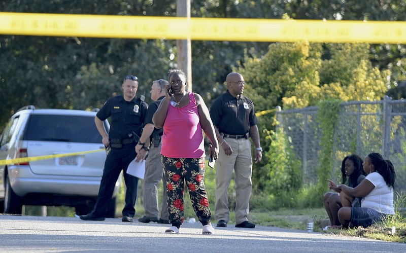 A woman talks on a phone following an afternoon shooting in the 3100 block of 7th Avenue on Sunday, Aug. 23, 2015, in Chattanooga that left a 14-year-old boy with gunshot wounds to his arm, leg and chest.