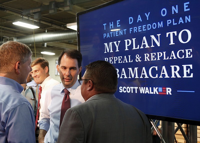 
              Republican presidential candidate, Wisconsin Gov. Scott Walker, center, visits with two men after he presented his health care plan, during a visit to Cass Screw Machine Products, Tuesday, Aug. 18, 2015, in Brooklyn Center, Minn. (AP Photo/Jim Mone)
            