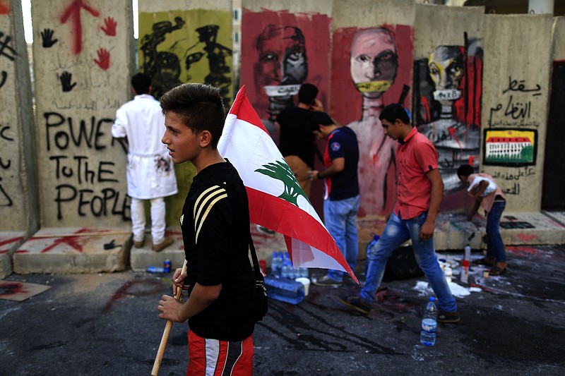 
              Lebanese activists protest in front a concrete wall installed by authorities, and quickly covered with graffiti, near the main Lebanese government building a day after violent anti-government protests, in downtown Beirut, Lebanon, Monday, Aug. 24, 2015. Organizers of the "You stink" protests that have captivated the Lebanese capital postponed anti-government demonstrations set for Monday evening after a night of violent clashes with police during which dozens of protesters and police officers were wounded. (AP Photo/Hassan Ammar)
            