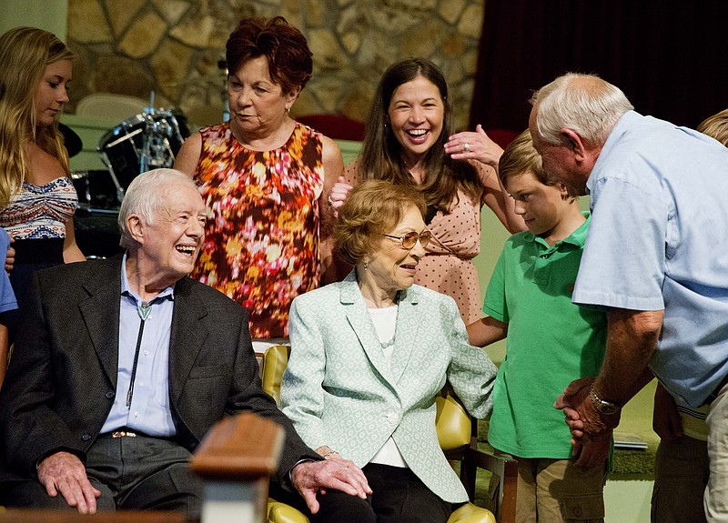 Former President Jimmy Carter, left, sits with his wife Rosalynn as they pose for photos with Bill Bush, of Adel, Ga., from right, his grandson Carson Shirley, 9, daughter Lara Norris, and wife Pat Bush after Carter taught Sunday School class at Maranatha Baptist Church in his hometown Sunday, Aug. 23, 2015, in Plains, Ga.