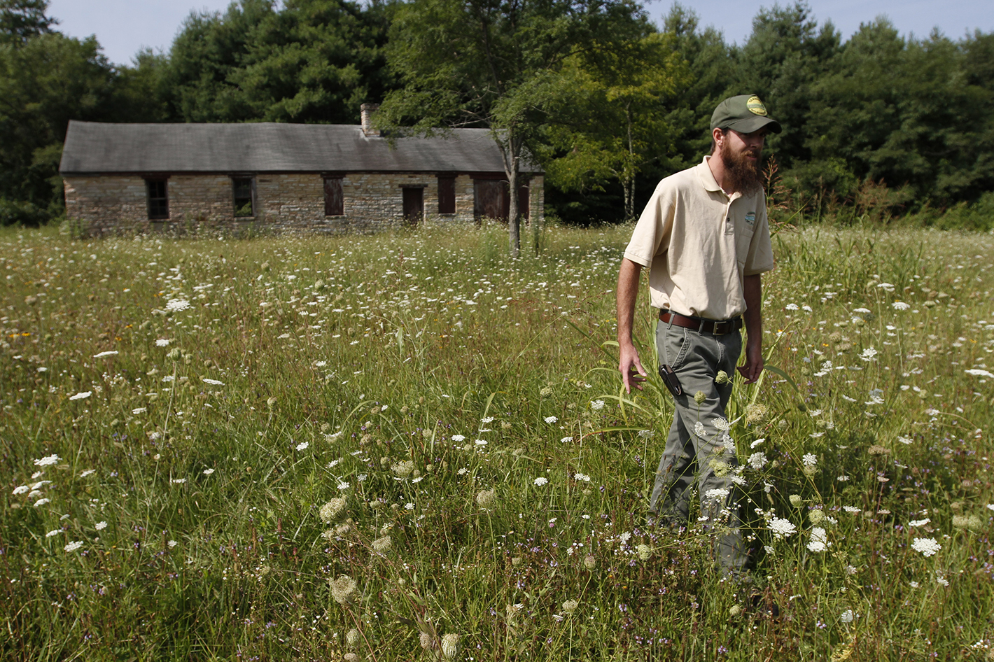 Staff Photo by Dan Henry / The Chattanooga Times Free Press- 7/30/14. Robbie Taylor walks through a field in front of a Civilian Conservation Corps structure in the Bledsoe State Forest on July 30, 2014. Local officials and fans of the CCC are looking to preserve the camp and other structures west of Pikeville, Tennessee.