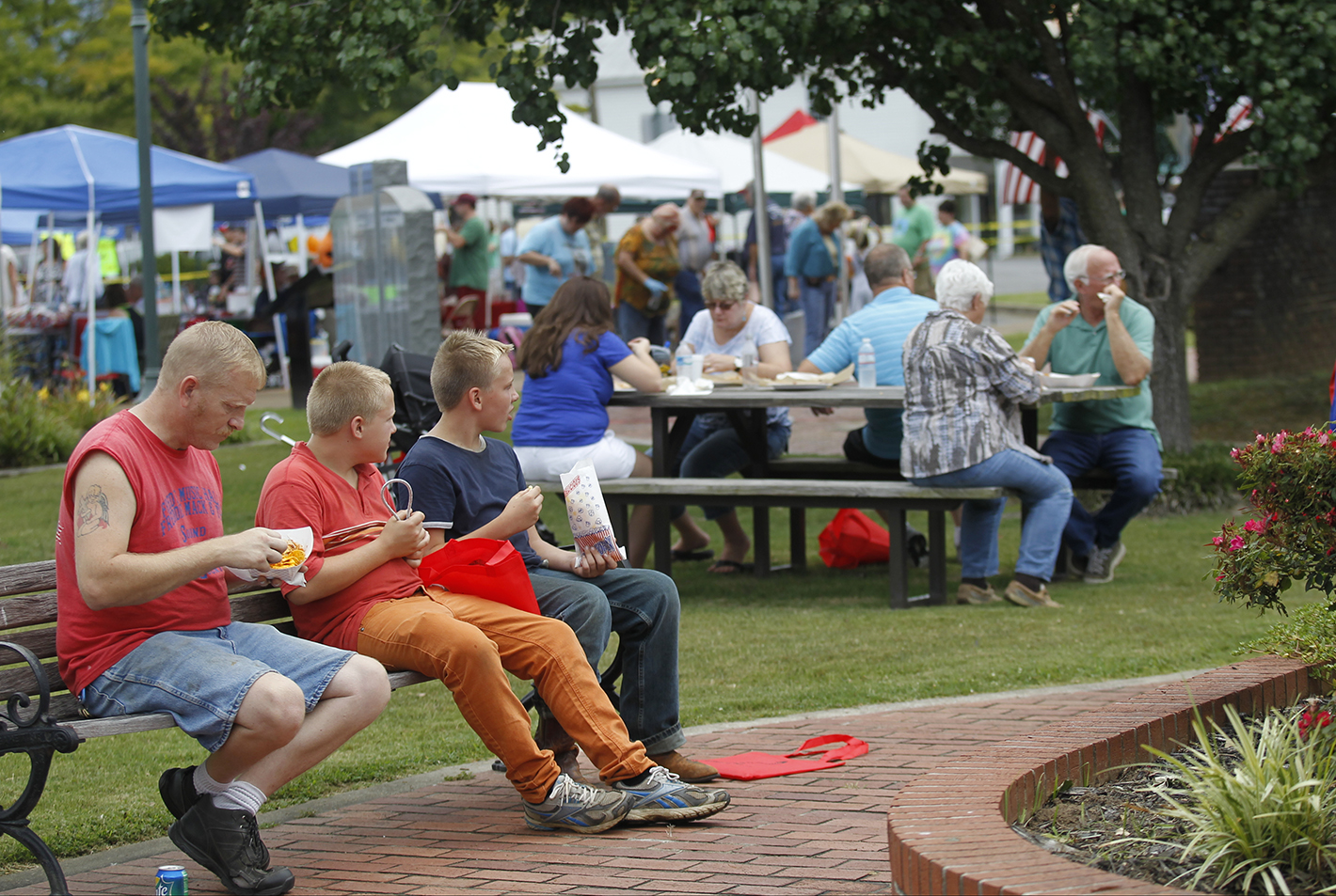 People eat lunch in Veterans Memorial Park on Saturday, Aug. 2, 2014, at the Dade County Days Festival in Trenton, Ga. The festival included a day of musical performances, vendors, inflatables, and a rubber duck race.