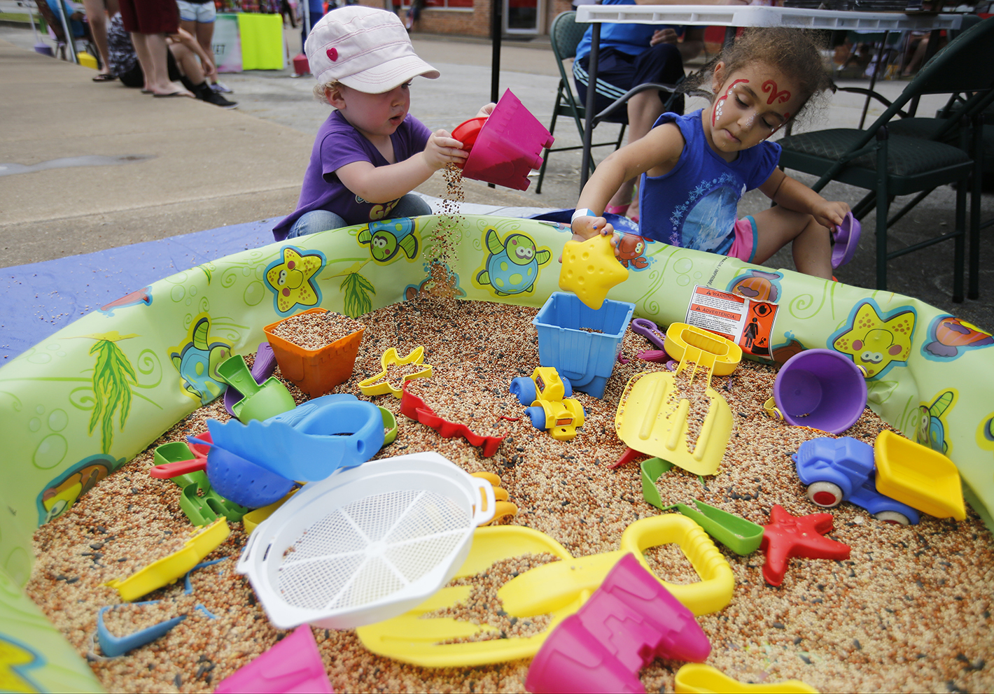 Norajean Worland, left, and Amaya Wilson play in a sandbox filled with birdseed Saturday, Aug. 2, 2014, at the Dade County Days Festival at Veterans Memorial Park in Trenton, Ga. The festival included a day of musical performances, vendors, inflatables, and a rubber duck race.