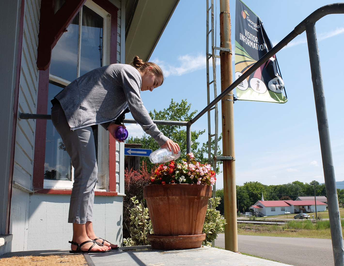 Dade County Chamber and Welcome Center Information Specialist Madeline Barton waters the flowers on the porch of the old Trenton Depot on Tuesday Work continues on the new offices for the Chamber of Commerce and Visitors Center to be located in the old Dade County Courthouse. The courthouse is being updated for ADA compliance.