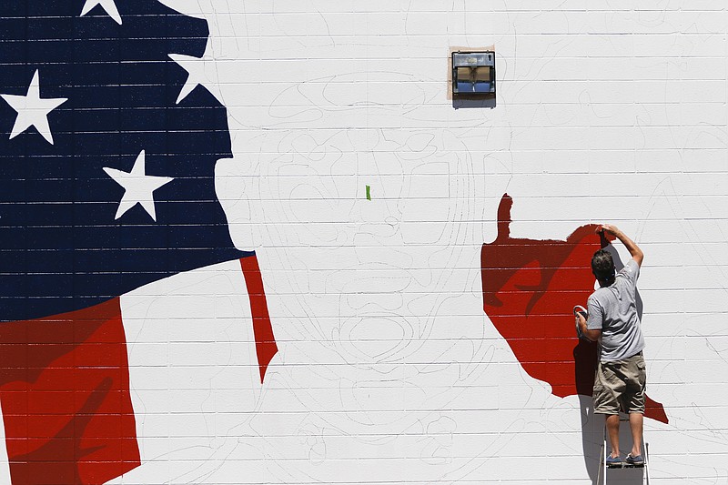 Kevin Bate works on a mural Tuesday to memorialize the five servicemen who were slain in the July 16 shootings in Chattanooga. The mural is being painted a few blocks from Bate's home at the Tennessee Wholesale Florist building that borders McCallie Avenue.