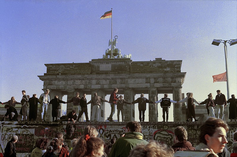 
              FILE - In this Nov. 10, 1989 file photo Berliners sing and dance on top of The Berlin Wall in front of the Brandenburg Gate to celebrate one day after the opening of East-West German borders. East German leader Walter Ulbricht billed the 155-kilometer (96-mile) barrier as an "anti-fascist protective wall," protecting his citizens from the West, but in reality it was to stop his citizens from fleeing for the West. (AP Photo/Thomas Kienzle, File)
            