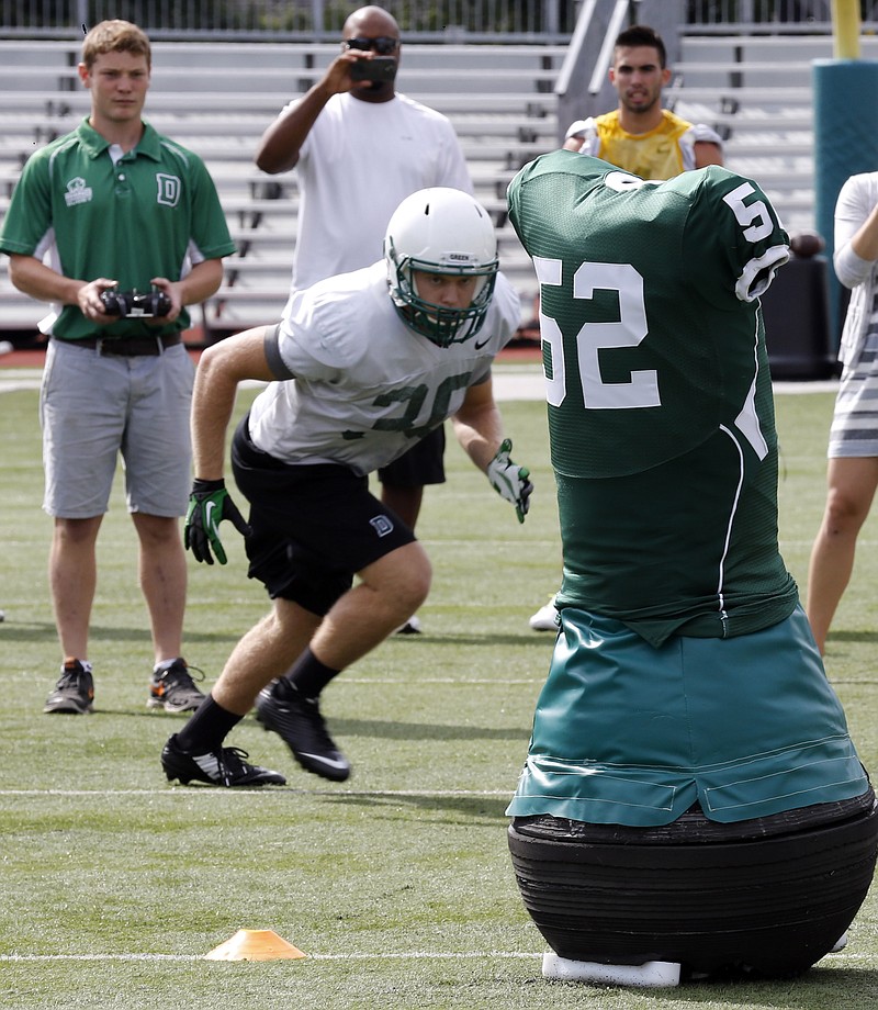 
              Dartmouth College Engineering graduate Quinn Connell, upper left, controls the movement of the team's “Mobile Virtual Player” during college football practice Wednesday Aug. 26, 2015, in Hanover, N.H. In an effort to avoid concussions, the team practices with its new “Mobile Virtual Player,” which the school says is the only powered device that simulates a real football player in size, weight, agility and speed. (AP Photo/Jim Cole)
            