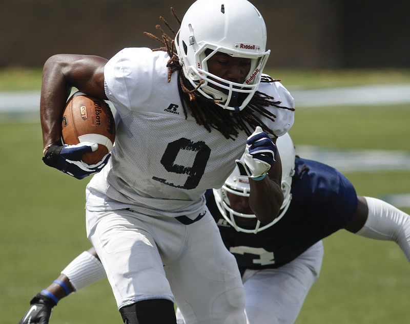 Staff Photo by Dan Henry / The Chattanooga Times Free Press- 8/15/14. UTC's Alphonso Stewart (9) dodges a tackle by Dee Virgin (3) during a scrimmage at preseason camp on August 15, 2014. 