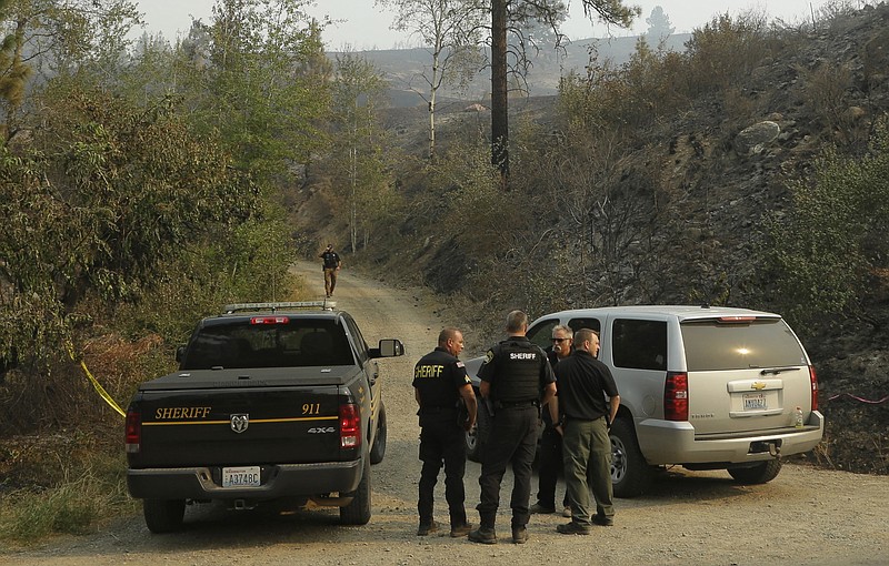 
              FILE -  In this Thursday, Aug. 20, 2015, file photo, Okanogan County Sheriff's deputies guard the entrance to Woods Canyon Road near Twisp, Wash. Three firefighters were killed after their engine rushed up a steep gravel road and crashed down a 40-foot embankment near the mountain town of Twisp. Before they could escape, they were overrun by flames. (AP Photo/Ted S. Warren, File)
            