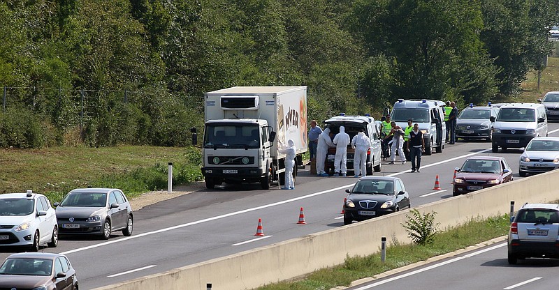 Police stands near a truck that stands on the shoulder of the highway A4 near Parndorf south of Vienna, Austria, Thursday, Aug 27, 2015. At least 20 migrants were found dead in the truck parked on the Austrian highway leading from the Hungarian border, police said.