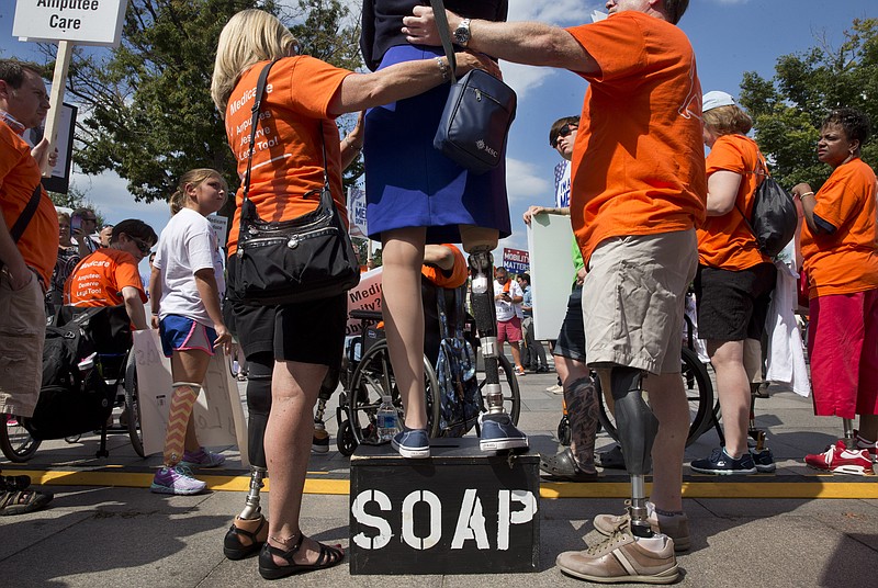 
              Theresa Sarea, of New York City, center, is helped to stand up on her prosthesis as she speaks to the Amputee Coalition during a protest against a change in Medicare payment policy for lower limb prosthetics including artificial feet, in Washington, Wednesday, Aug. 26, 2015. (AP Photo/Jacquelyn Martin)
            