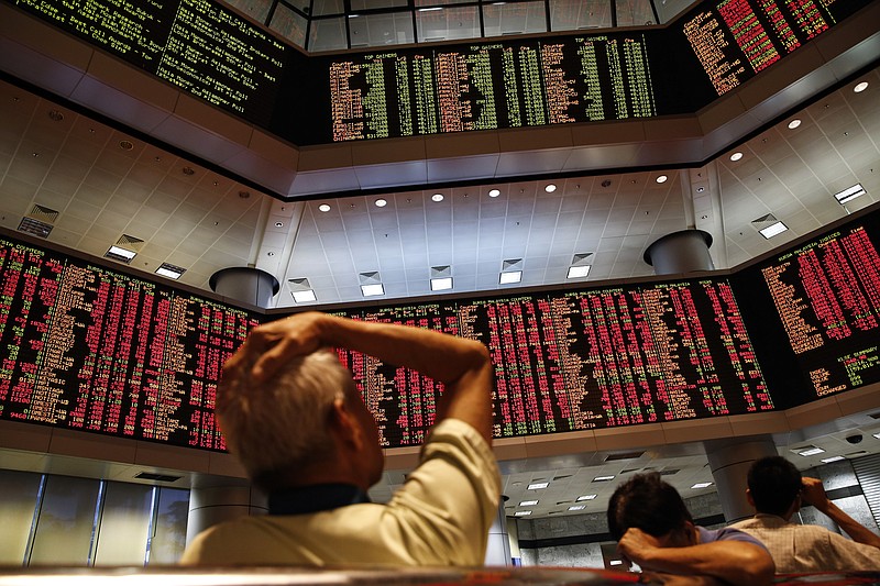 People watch trading boards at a private stock market gallery in Kuala Lumpur, Malaysia on Monday. Stocks tumbled across Asia as investors shaken by the sell-off last week unloaded shares in practically every sector.