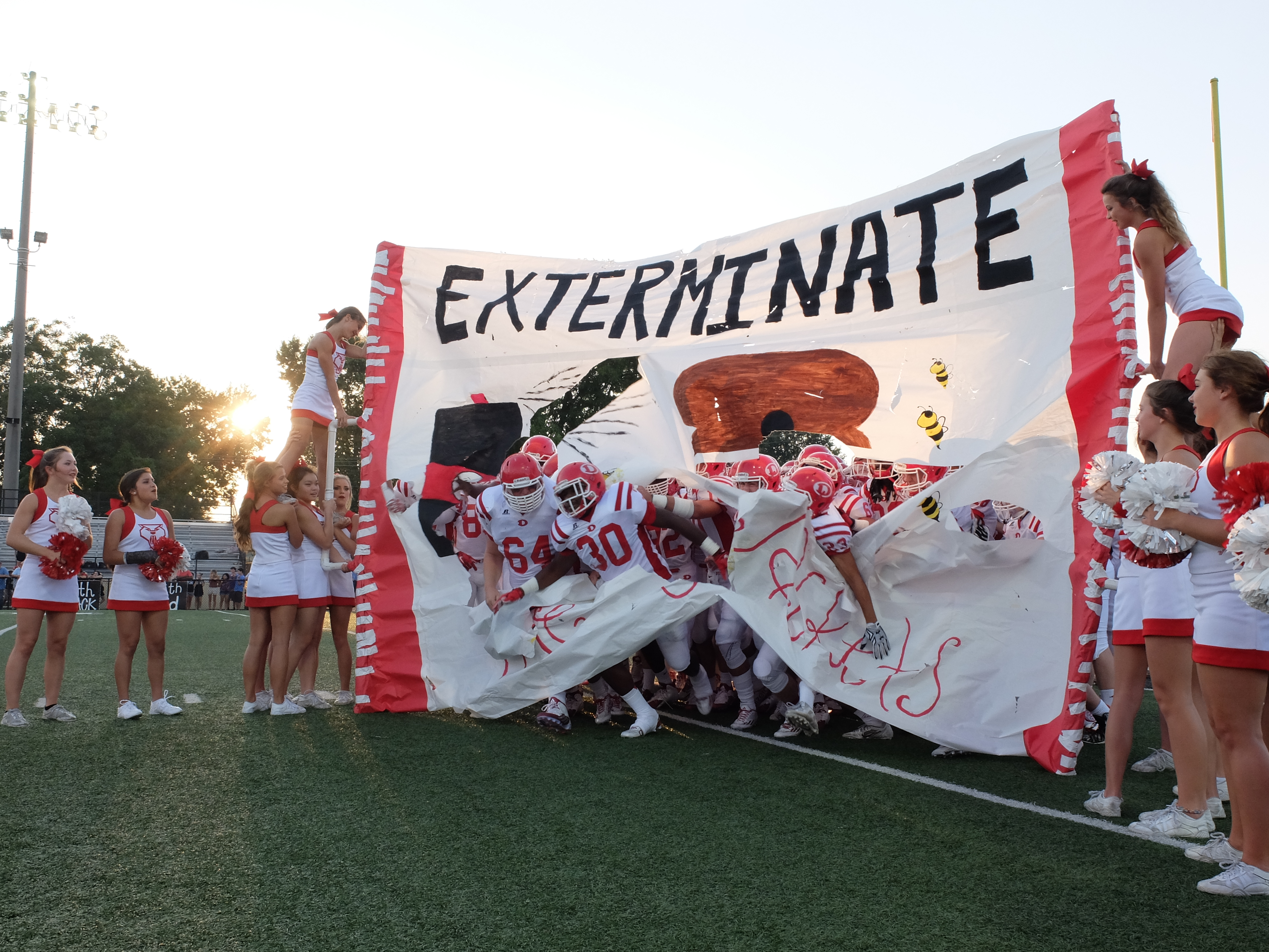 Dalton's Andrew Williams (64), and Logan Pender (30) break through the banner held by Catamount Cheerleaders at the outset of the game with Calhoun Friday.