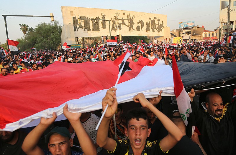 
              Protesters chant slogans in support of Iraqi Prime Minister Haider al-Abadi as they carry a large national flag during a rally in Tahrir Square in Baghdad, Iraq, Friday, Aug. 28, 2015. Friday's protesters were joined for the first time by followers of Muqtada al-Sadr, a radical, anti-American Shiite cleric. The protesters have staged weekly rallies since last month to press demands for reforms, better services and an end to corruption. (AP Photo/Karim Kadim)
            