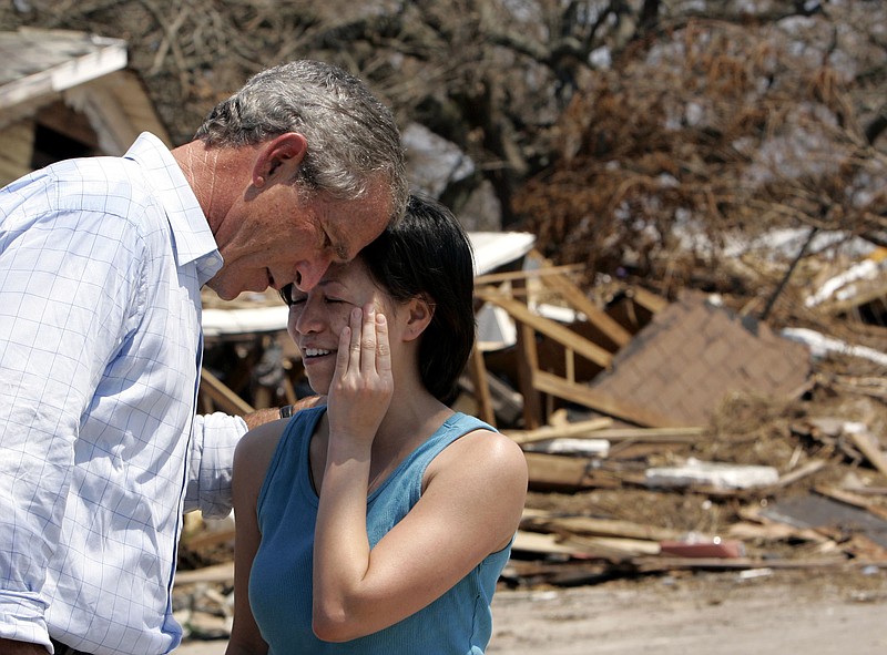 Then-President George W. Bush tries to comfort Kristine Nguyen during a 2005 walking tour of a neighborhood devastated by Hurricane Katrina.