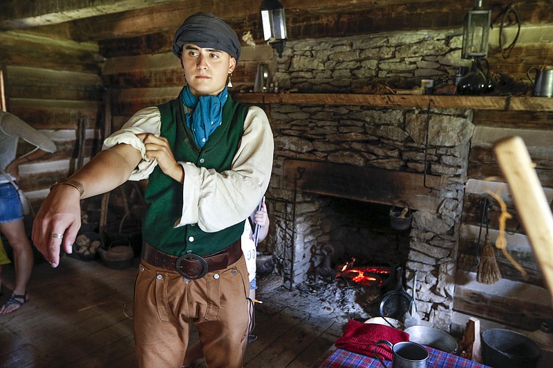 Tennessee State Park Ranger and historical re-enactor Luke Mason rolls up his sleeves in a replica cabin at the Cherokee Heritage Festival at Red Clay State Park on Saturday, Aug. 29, 2015, in Cleveland, Tenn. The festival marks the first time since 1838 that the three federally recognized Cherokee tribes have met at the park.
