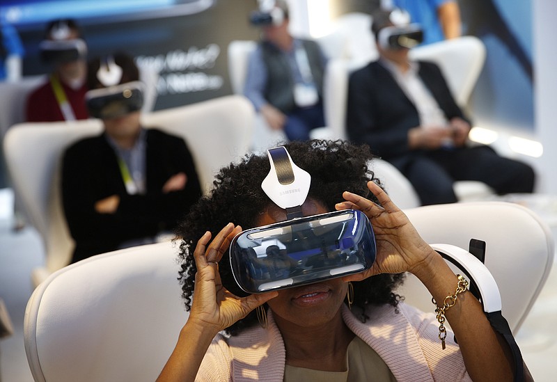 
              FILE - In this Jan. 6, 2015 file photo, Yasmin Moorman looks into the Galaxy Gear VR headset at the Samsung booth during the International CES, in Las Vegas.  While more than 1,500 attendees are expected on Saturday, Aug. 29, 2015, at the VRLA expo, the event probably won’t feel very crowded. That’s because headset-wearing convention goers will be transported to other worlds during the second-annual celebration of virtual reality at the Los Angeles Convention Center. (AP Photo/John Locher, File)
            