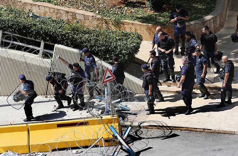 
              Lebanese riot policemen pass under barbed wire barriers, as they start deploying around the government building where anti-government protesters hold their daily demonstrations, in downtown Beirut, Lebanon, Saturday, Aug. 29, 2015. The London-based rights group Amnesty is calling on Lebanese authorities to investigate allegations that security forces have used excessive force to disperse rallies protesting the government failure to deal with garbage pilling in the streets. The statement comes ahead of a major rally planned in Beirut Saturday amid worries it would also descend into clashes. (AP Photo/Hussein Malla)
            