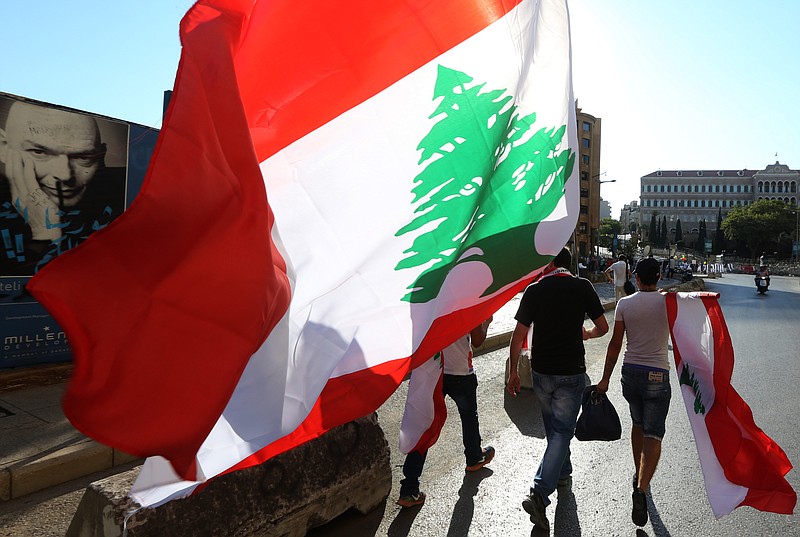 
              Lebanese anti-government protesters carry Lebanese flags as they walk towards the government building, background, during a demonstration against the trash crisis and government corruption, in downtown Beirut, Lebanon, Saturday, Aug. 29, 2015. Hundreds of people began gathering Saturday amid tight security in downtown Beirut, ahead of a major rally that is expected to be the largest of protests that began last week. The government's failure to resolve the crisis has evolved into wider protests against a political class that has dominated Lebanon since the end of the country's civil war in 1990. (AP Photo/Bilal Hussein)
            