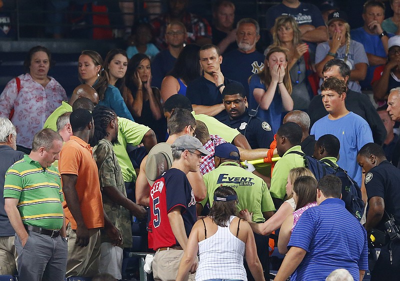 Rescue workers carry an injured fan from the stands at Turner Field during a baseball game between Atlanta Braves and New York Yankees Saturday, Aug. 29, 2015, in Atlanta. 