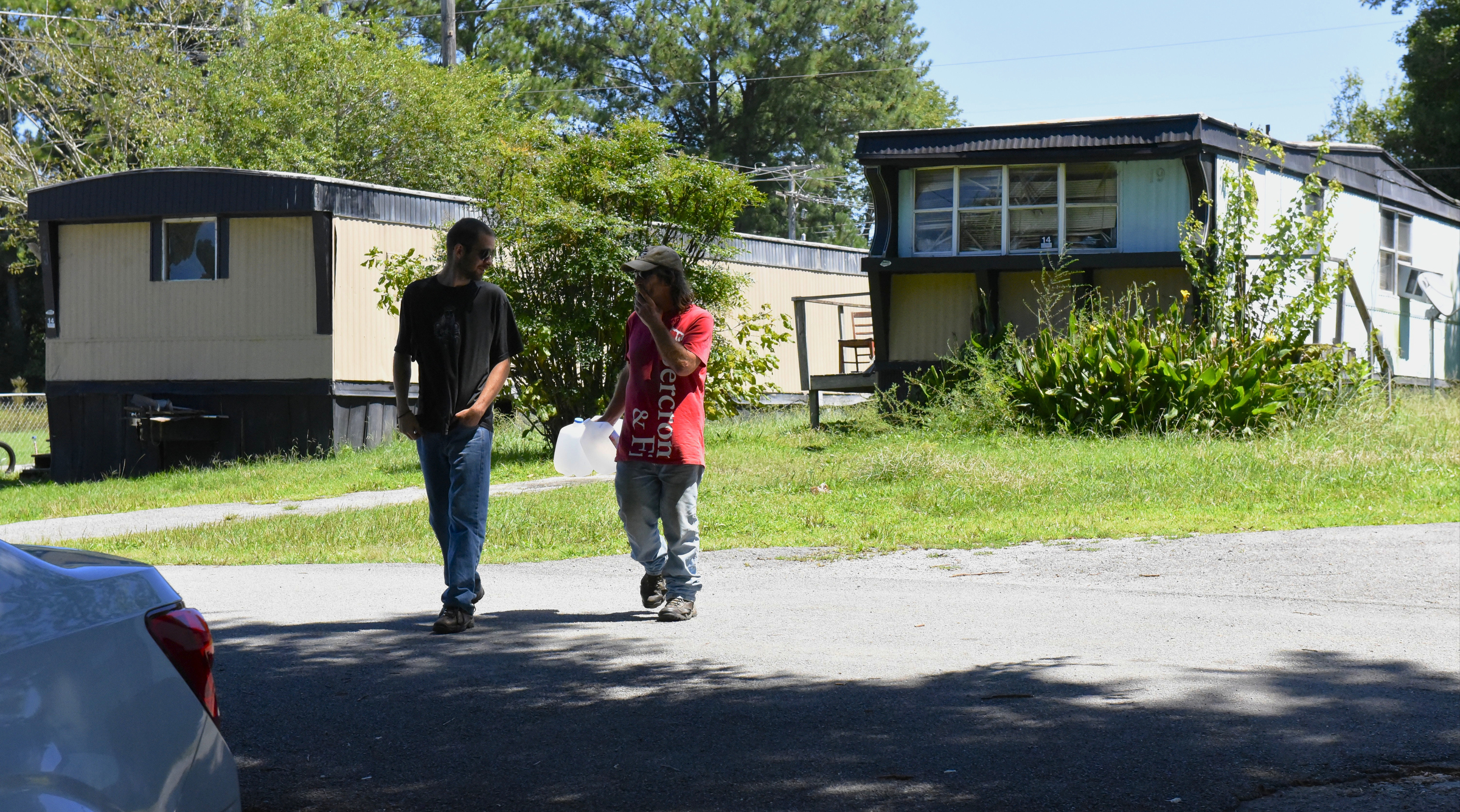Aaron Kelley, left, and Joe Strefling gather water bottles at the Pear Pines Mobile Home Park on Tuesday, Aug. 25, 2015, in LaFayette, Ga., before a friend with a car makes a run to her house to fill them for residents. Few residents remain after the landlord's financial problems caused water to be turned off at the property several weeks ago.