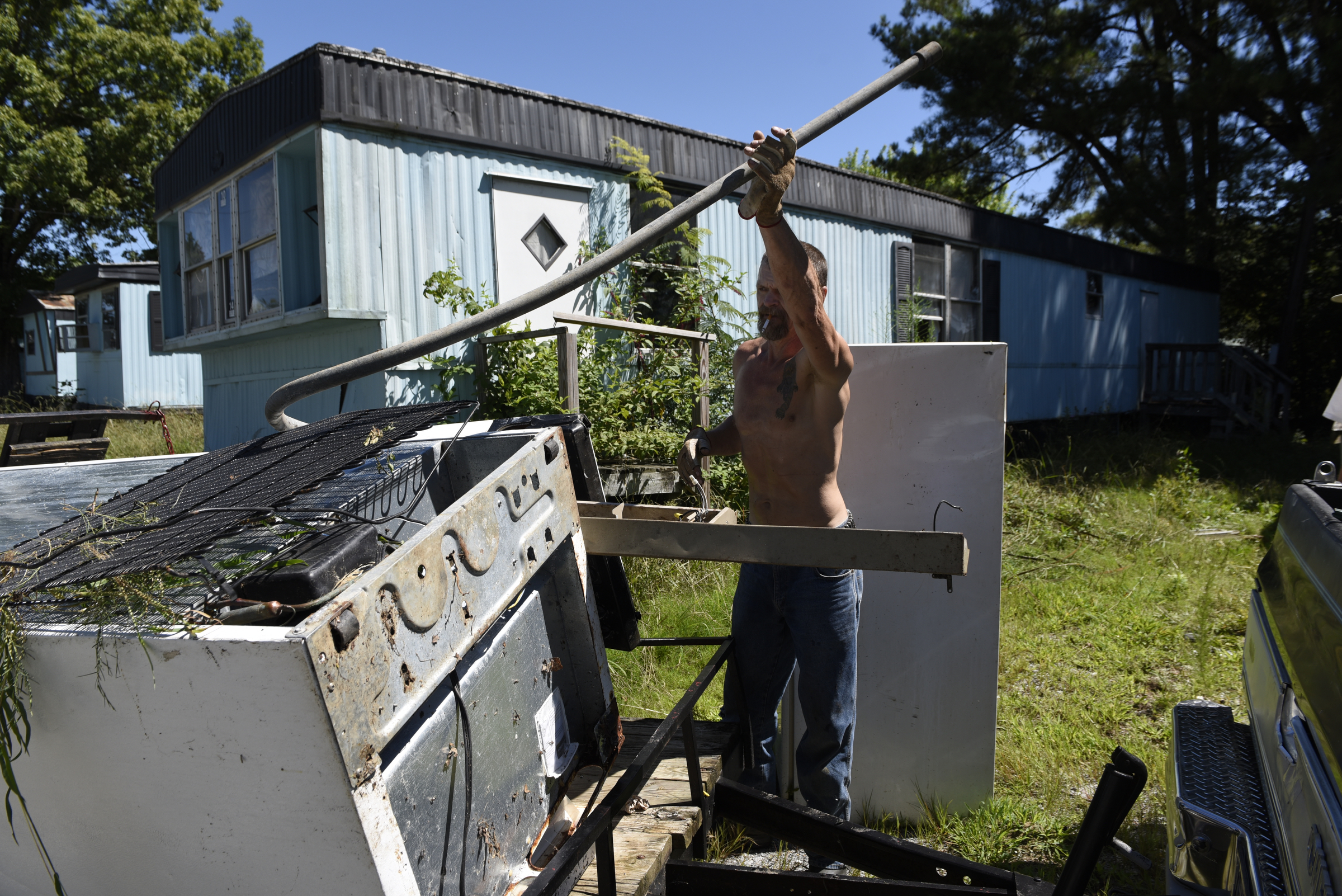 Resident Andy Anderson collects appliances and other scrap metal he is salvaging from abandoned mobile homes at the Pear Pines Mobile Home Park on Tuesday, Aug. 25, 2015, in LaFayette, Ga.