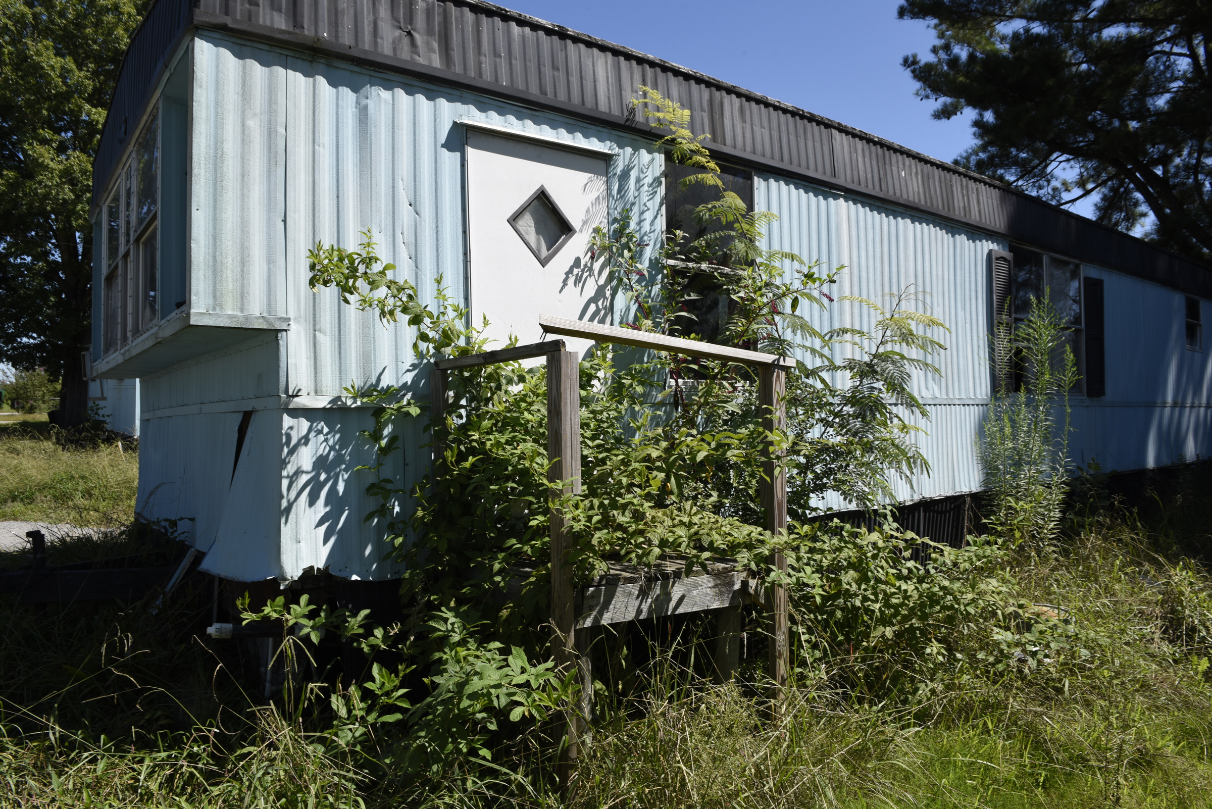 An overgrown, abandoned mobile home is seen at the Pear Pines Mobile Home Park on Tuesday, Aug. 25, 2015, in LaFayette, Ga.