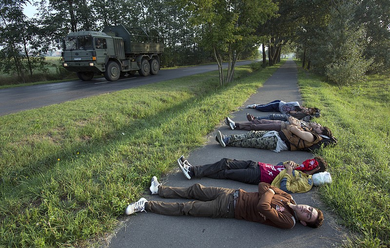 
              A Hungarian Army truck drives past a group of Afghan men who crossed from nearby Serbia and sleeping on a bicycle path in Morahalom, Hungary, Sunday, Aug. 30, 2015. Migrants fearful of death at sea in overcrowded and flimsy boats have increasingly turned to using a land route to Europe through the Western Balkans. (AP Photo/Darko Bandic)
            