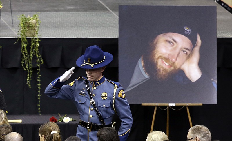 A Washington State trooper salutes as he stands near a portrait of Andrew Zajac at a memorial service for three firefighters killed in a wildfire, Sunday, Aug. 30, 2015, in Wenatchee, Wash. Zajac, Richard Wheeler and Thomas Zbyszewski died Aug. 19 in a fire near Twisp, Wash. 