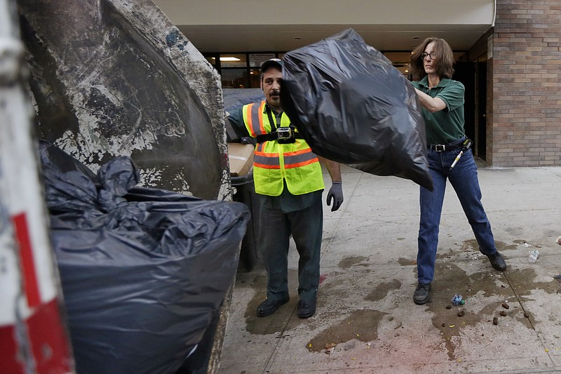 
              New York University professor and Department of Sanitation of New York anthropologist-in-residence Robin Nagle, right, tosses a bag of garbage into the truck as she accompanies sanitation worker Joe Damiano, during his morning rounds, Wednesday, Aug. 12, 2015, in New York. Nagle studies the refuse along the curbs of the nation's biggest city as a mirror into the lives of its 8.5 million residents. (AP Photo/Richard Drew)
            